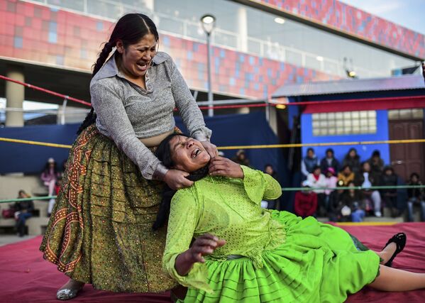 Bolivian wrestler Ana Luisa Yujra (L), aka Jhenifer Two Faces and Lidia Flores, aka Dina, The Queen of the Ring, both members of the Fighting Cholitas, fight at Sharks of the Ring wrestling club in El Alto, Bolivia, on November 24, 2019. - Sputnik International