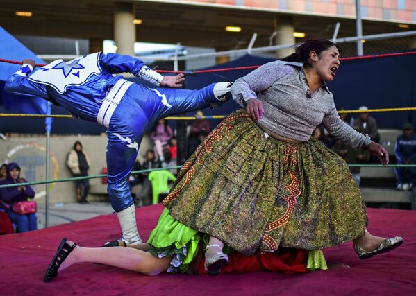 Bolivian wrestler Ana Luisa Yujra (R), aka Jhenifer Two Faces, Lidia Flores (on the canvas), aka Dina, The Queen of the Ring, both members of the Fighting Cholitas, and a wrestler fight at Sharks of the Ring wrestling club in El Alto, Bolivia, on November 24, 2019. - Sputnik International