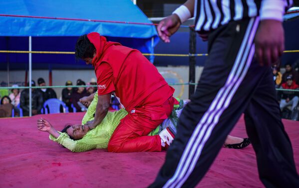 Bolivian wrestler Lidia Flores (on the canvas), aka Dina, The Queen of the Ring, member of the Fighting Cholitas, fights with a male wrestler at Sharks of the Ring wrestling club in El Alto, Bolivia, on November 24, 2019.  - Sputnik International