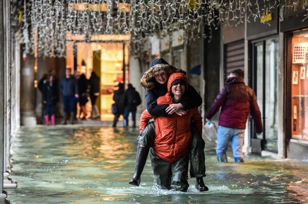 A person carries another across a flooded arcade on 24 November 2019 in Venice during the high tide Acqua Alta meteorological phenomenon. - Sputnik International