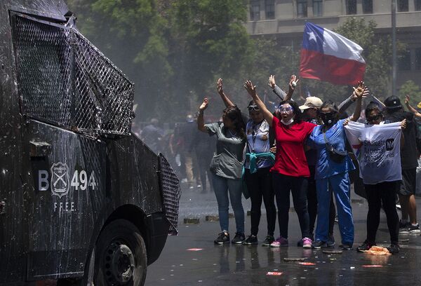 Demonstrators stand in front of a riot police vehicle during a protest against the Chilean government in front of the La Moneda presidential palace in Santiago on 26 November 2019. - Sputnik International