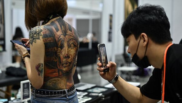 (FILES) In this file photo taken on November 29, 2019, a man takes pictures of a woman with tattoos during the International Malaysia Tattoo Expo in Kuala Lumpur - Sputnik International