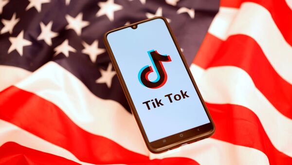 TikTok logo is displayed on the smartphone while standing on the U.S. flag - Sputnik International