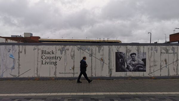 A man in West Bromwich town centre walks past a wall featuring historical images of the 'Black Country' region of the West Midlands - Sputnik International