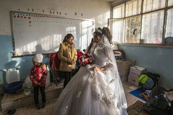 Hanan, a displaced Syrian woman wears her wedding dress at her temporary home, a school building transformed into a makeshift shelter, before being wed to Mohammad in the northern Syrian city of Hasakeh on December 1, 2019. Hanan and Mohammad fled with their families from the northeastern town of Ras al-Ain following the Turkish offensive against the Kurdish-dominated region, were wedded after being in love for three years.  - Sputnik International