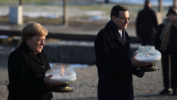 Polish Prime Minister Mateusz Morawiecki and German Chancellor Angela Merkel hold candles at the Monument to the Victims at the former Nazi German concentration and extermination camp Auschwitz II-Birkenau near Oswiecim, Poland December 6, 2019. - Sputnik International