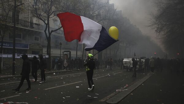 A man waves a French flag during a demonstration in Paris, Thursday, Dec. 5, 2019. Small groups of protesters are smashing store windows, setting fires and hurling flares in eastern Paris amid mass strikes over the government's retirement reform. - Sputnik International