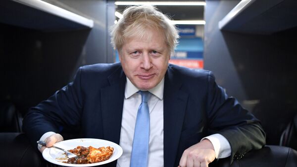 Britain's Prime Minister Boris Johnson eats a portion of pie on the campaign bus after a visit to the Red Olive catering company in Derby, Britain December 11, 2019 on the final day of campaigning before a general election - Sputnik International