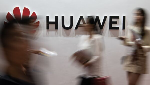 (FILES) In this file photo taken on August 2, 2019 people walk past a Huawei logo during the Consumer Electronics Expo in Beijing. - Chinese tech giant Huawei, facing US criminal charges and economic sanctions, is planning to relocate its telecommunications research from the United States to Canada, founder Ren Zhengfei said in an interview published on December 3, 2019 - Sputnik International