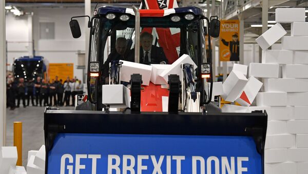 Britain's Prime Minister and Conservative party leader Boris Johnson drives a Union flag-themed JCB, with the words Get Brexit Done inside the digger bucket, through a fake wall emblazoned with the word GRIDLOCK, during a general election campaign event at JCB construction company in Uttoxeter, Staffordshire, on December 10, 2019. - Sputnik International