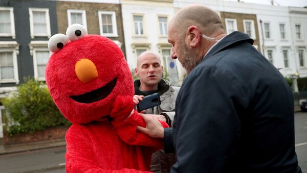 A member of Britain's opposition Labour Party leader Jeremy Corbyn's security detail argues with a person dressed as Sesame Street character Elmo as Corbyn returns from a polling station after voting in the general election in London, Britain, December 12, 2019 - Sputnik International