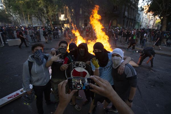Demonstrators pose for a picture near a bonfire at a blocked street during a protest against the government of Chilean President Sebastian Pinera, in Santiago, on December 06, 2019 - Sputnik International