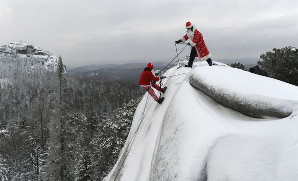 Mikhail Morin, a member of the search and rescue squad Rescuer, dressed as Santa Claus, left, and Dmitry Ivanov participate in the final rock training of the year on the syenite rock Fourth Pillar in Stolby Nature Sanctuary outside the Siberian city of Krasnoyarsk, Russia - Sputnik International