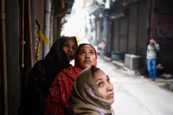 Women look at a factory site where a fire broke out a day before, in Anaj Mandi area of New Delhi on December 9, 2019 - Sputnik International