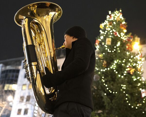 A member of the Rudersdorf Music Society brass band plays Christmas carols with his tuba at the small Christmas market in Vienna's Mariahilfer Street on December 9, 2019 in Vienna, Austria - Sputnik International