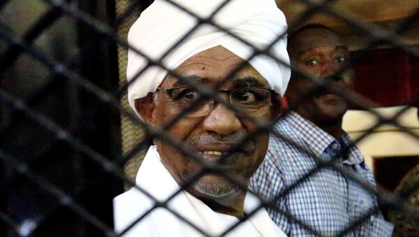 FILE PHOTO: Sudanese former president Omar Hassan al-Bashir smiles inside a cage as he faces corruption charges in a court in Khartoum, Sudan, August 31, 2019 - Sputnik International