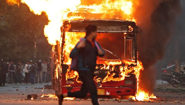 A man runs past a burning bus that was set on fire by demonstrators during a protest against a new citizenship law, in New Delhi, India, December 15, 2019 - Sputnik International