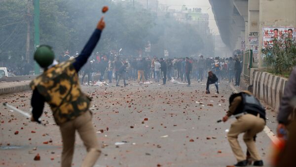 A riot police officer throws a piece of brick towards demonstrators during a protest against a new citizenship law in Seelampur, area of Delhi, India  December 17, 2019 - Sputnik International