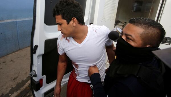 A policeman escorts an inmate injured during a fight at El Porvenir prison, as they arrive at a hospital in Tegucigalpa, Honduras, December 22, 2019 - Sputnik International