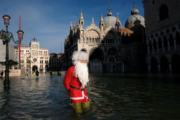 A man dressed as Santa Claus wades through floodwater in St. Mark's Square during high tide in Venice, Italy, 23 December 2019.  - Sputnik International