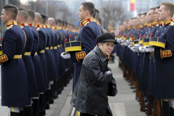 A woman walks by honor guard soldiers during a memorial religious service at the Heroes' cemetery, to honor those killed in the anti-communist  uprising, in Bucharest, Romania. - Sputnik International