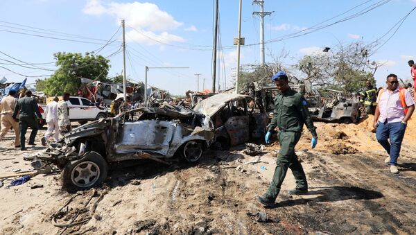 A Somali police officer walks past a wreckage at the scene of a car bomb explosion at a checkpoint in Mogadishu - Sputnik International