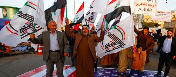 Iraqi people walk on a U.S. flag in a protest after an airstrike at the headquarters of Kataib Hezbollah militia group in Qaim, in the holy city of Najaf, Iraq December 30, 2019. - Sputnik International