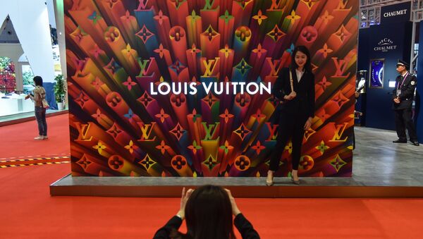A woman poses for a picture next to a Louis Vuitton stand during the second China International Import Expo in Shanghai on november 6, 2019. - Sputnik International