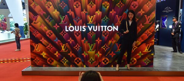 A woman poses for a picture next to a Louis Vuitton stand during the second China International Import Expo in Shanghai on november 6, 2019. A woman poses for a picture next to a Louis Vuitton stand during the second China International Import Expo in Shanghai on november 6, 2019. - Sputnik International