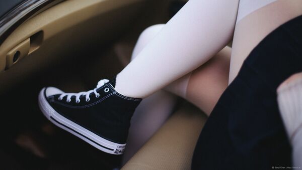 A girl wearing Converse shoes, white stockings and a black skirt is pictured sitting in a car. - Sputnik International