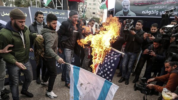 Palestinians in Gaza City burn a US and an Israeli flag during a mourning ceremony organised in honour of slain Iranian military commander Qasem Soleimani (portrait on banner) killed in a US air strike a day earlier, on January 4, 2020. - Sputnik International
