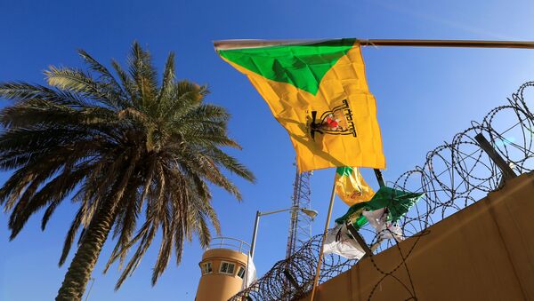 member of Hashd al-Shaabi (paramilitary forces) holds a flag of Kataib Hezbollah - Sputnik International