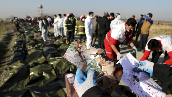  A rescue worker shows pictures of a girl recovered from a Ukrainian plane crash site in Shahedshahr, southwest of the capital Tehran, Iran - Sputnik International