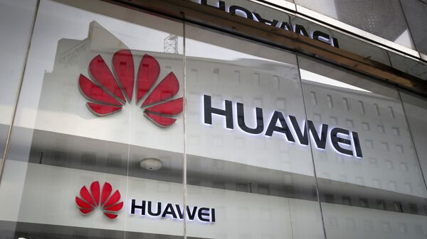 In this Jan. 29, 2019, file photo, the logos of Huawei are displayed at its retail shop window reflecting the Ministry of Foreign Affairs office in Beijing. - Sputnik International