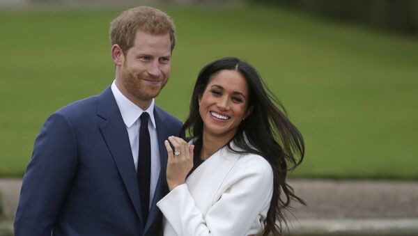 In this file photo Britain's Prince Harry stands with his fiance US actress Meghan Markle as she shows off her engagement ring whilst they pose for a photograph in the Sunken Garden at Kensington Palace in west London on November 27, 2017, following the announcement of their engagement - Sputnik International