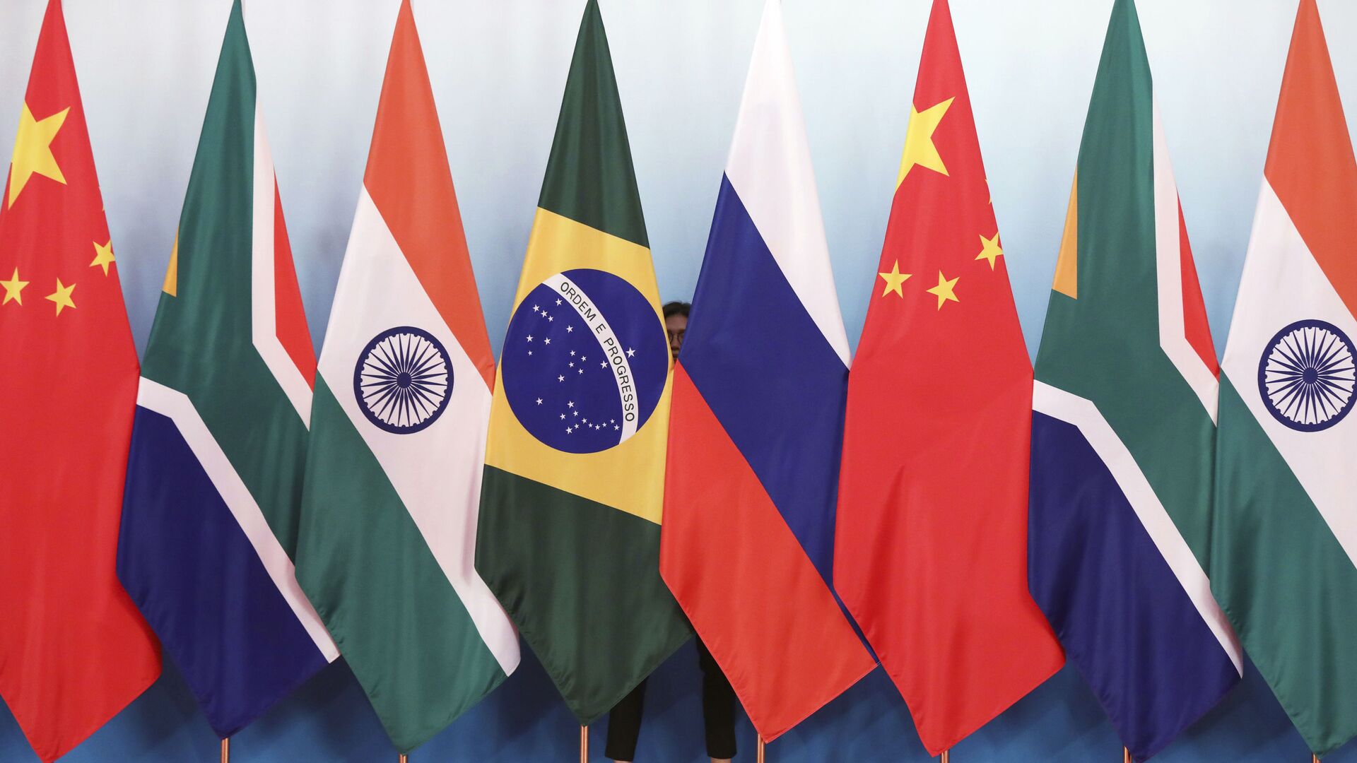 Staff worker stands behinds national flags of Brazil, Russia, China, South Africa and India to tidy the flags ahead of a group photo during the BRICS Summit at the Xiamen International Conference and Exhibition Center in Xiamen, southeastern China's Fujian Province, Monday, Sept. 4, 2017. - Sputnik International, 1920, 20.05.2022