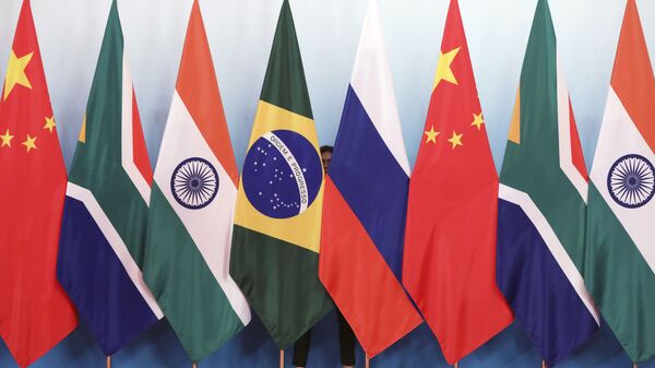 Staff worker stands behinds national flags of Brazil, Russia, China, South Africa and India to tidy the flags ahead of a group photo during the BRICS Summit at the Xiamen International Conference and Exhibition Center in Xiamen, southeastern China's Fujian Province, Monday, Sept. 4, 2017. - Sputnik International