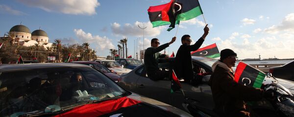 Libyans wave the national flag during commemorations to mark the second anniversary of the revolution that ousted Moammar Gadhafi in Benghazi, Libya, Friday, Feb, 15, 2013 - Sputnik International