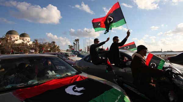 Libyans wave the national flag during commemorations to mark the second anniversary of the revolution that ousted Moammar Gadhafi in Benghazi, Libya, Friday, Feb, 15, 2013 - Sputnik International