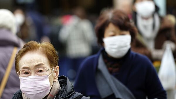 Pedestrians wear protective masks as they walk through a shopping district in Tokyo Thursday, Jan. 16, 2020. Japan's government said Thursday a man treated for pneumonia after returning from China has tested positive for the new coronavirus identified as a possible cause of an outbreak in the Chinese city of Wuhan.  - Sputnik International