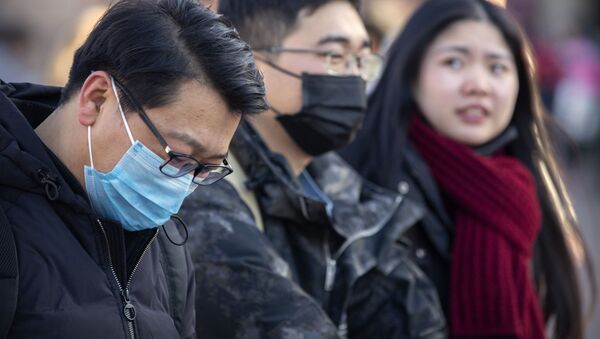 Travelers wear face masks as they walk outside of the Beijing Railway Station in Beijing, Monday, Jan. 20, 2020. China reported Monday a sharp rise in the number of people infected with a new coronavirus, including the first cases in the capital. The outbreak coincides with the country's busiest travel period, as millions board trains and planes for the Lunar New Year holidays. - Sputnik International