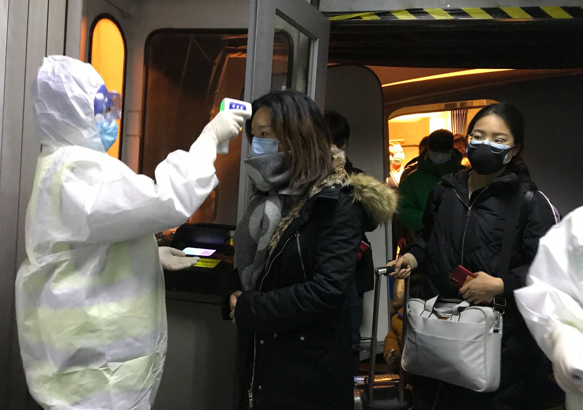 Health Officials in hazmat suits check body temperatures of passengers arriving from the city of Wuhan Wednesday, Jan. 22, 2020, at the airport in Beijing, China - Sputnik International, 1920, 07.09.2021