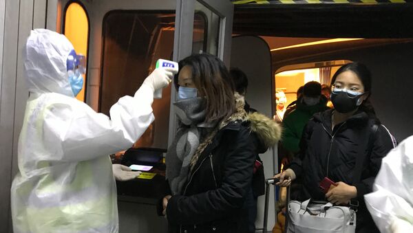 Health Officials in hazmat suits check body temperatures of passengers arriving from the city of Wuhan Wednesday, Jan. 22, 2020, at the airport in Beijing, China - Sputnik International