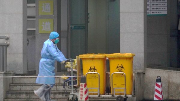 FILE - In this Wednesday, Jan. 22, 2020, file photo, a staff member moves bio-waste containers past the entrance of the Wuhan Medical Treatment Center in Wuhan, China, where some people infected with a new virus are being treated.  - Sputnik International