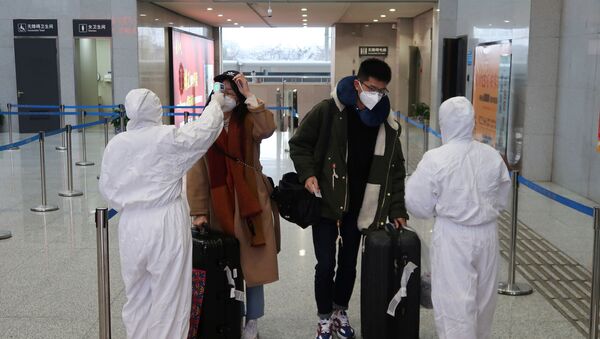 Workers in protective suits check the temperature of passengers arriving at the Xianning North Station on the eve of the Chinese Lunar New Year celebrations, in Xianning, a city bordering Wuhan to the north, in Hubei province, China January 24, 2020 - Sputnik International