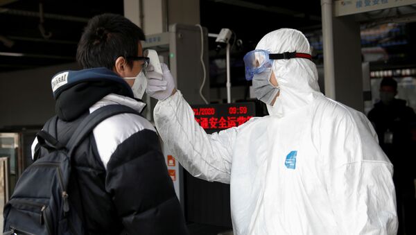 A worker in protective suit uses a thermometer to check the temperature of a man - Sputnik International