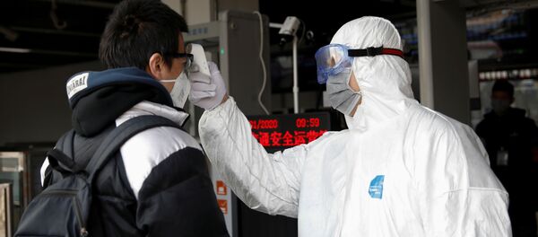 A worker in protective suit uses a thermometer to check the temperature of a man - Sputnik International