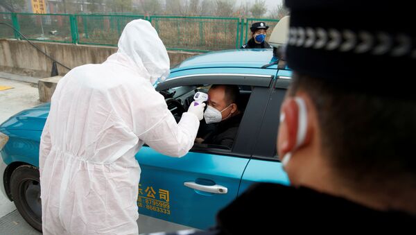 A medical worker in protective suit checks the body temperature of a driver at a checkpoint outside the city of Yueyang, Hunan Province, near the border to Hubei Province that is on lockdown after an outbreak of a new coronavirus, China, January 28, 2020.   - Sputnik International