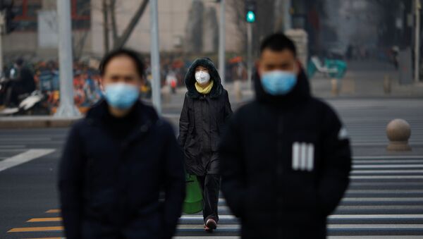 People wearing masks walk across a street as the country is hit by an outbreak of the new coronavirus, in Beijing, China January 28, 2020.  - Sputnik International