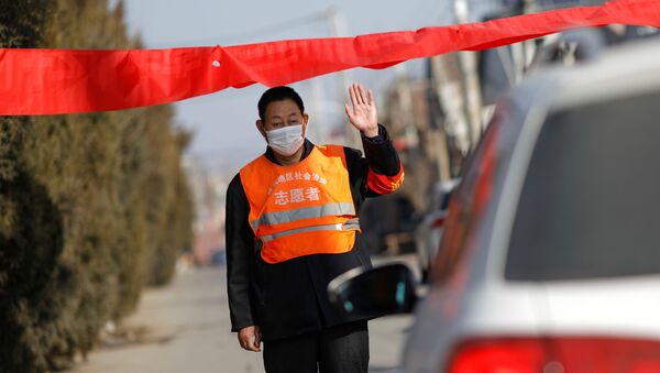 A village committee member wearing face mask and vest, stops a car for checking as he guards at the entrance of a community to prevent outsiders from entering - Sputnik International